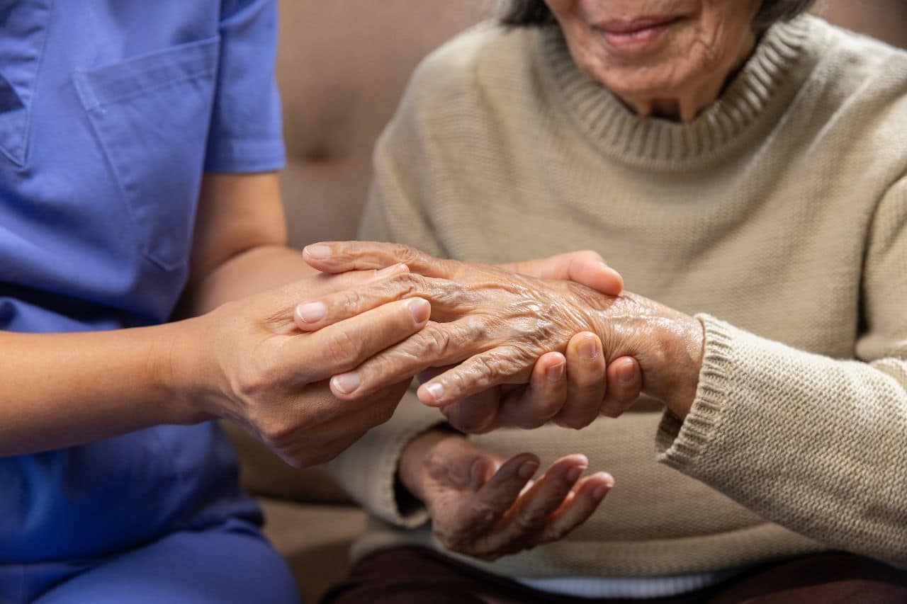 a nurse holding an old woman's hand